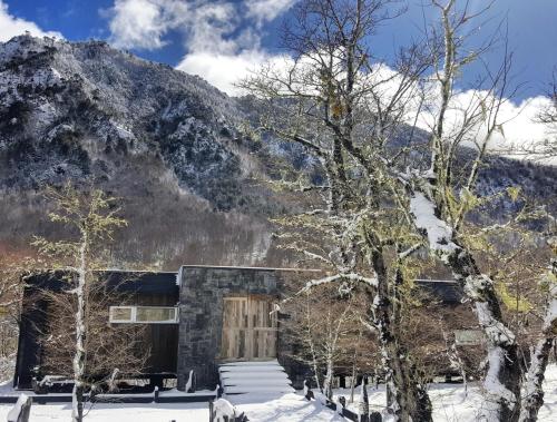 a building in the snow with a mountain in the background at Endemiko in Malalcahuello