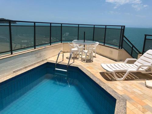 une piscine avec une table et des chaises sur un balcon dans l'établissement Cobertura frente ao mar, à Florianópolis