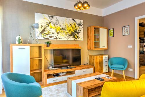 a living room with a television and blue chairs at Central Downtown Apartments in Budapest