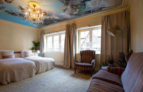een slaapkamer met 2 bedden en een plafond met een kroonluchter bij Place to Bee (Kamers) in Kortrijk