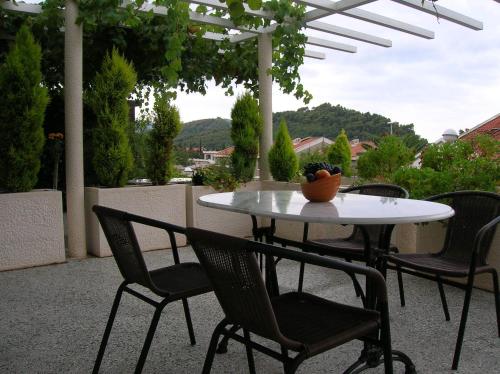 una mesa y sillas en un patio bajo una sombrilla blanca en Villa Mila, en Petrovac na Moru