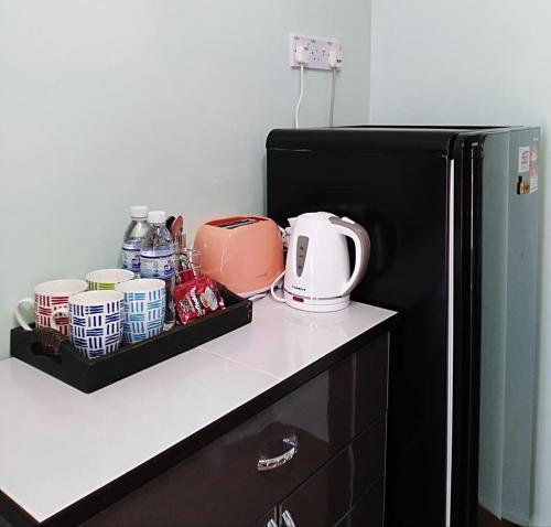 a kitchen counter with a black refrigerator and some dishes at M's Place Chalet Bed&Breakfast in George Town