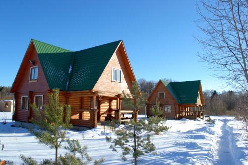 a large wooden house with green roofs in the snow at Fishing Club Litvinovo in Litvinovo