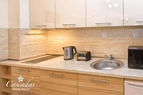 a kitchen counter with a sink and a microwave at Cascadas Family Resort in Sunny Beach