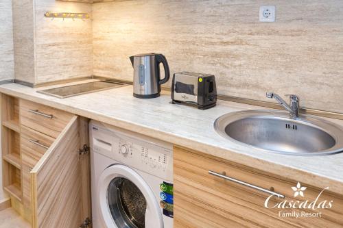 a kitchen with a sink and a washing machine on a counter at Cascadas Family Resort in Sunny Beach