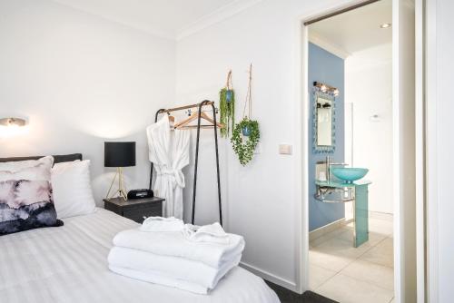 a bedroom with a bed with white sheets and a mirror at Madsen Retreat in Penguin