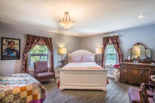 a bedroom with a bed and a dresser and two windows at Heartwood Inn in Drumheller