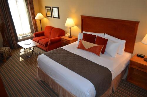 a hotel room with a large bed and a red chair at Inn at Cross Keys Station in Madras