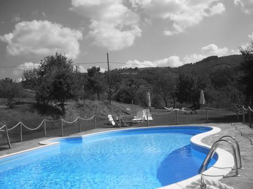 a blue swimming pool with chairs and a fence at La Pietraia in Panicale