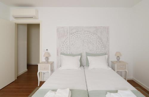 リスボンにあるDowntown Charming Apartmentのベッドルーム1室(白い大型ベッド1台、テーブル2台付)