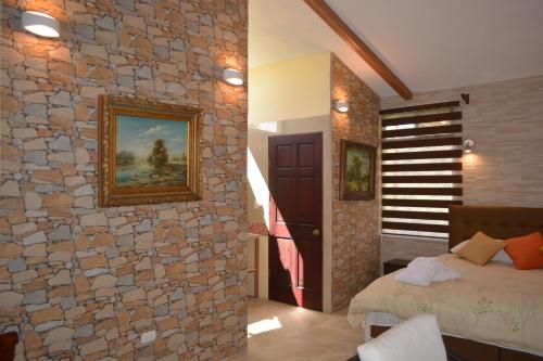 a bedroom with a stone wall with a bed in it at Finca Paraiso Mountain Retreat near San Jose Airport in Birrí