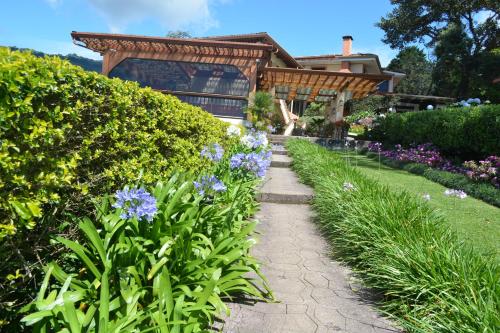 a garden with purple flowers and a house at Finca Paraiso Mountain Retreat near San Jose Airport in Birrí