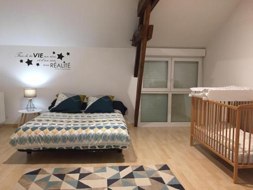 a bedroom with a bed and a crib at Gîtes d'Olbiche in Avranches