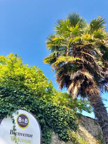 a sign in front of a palm tree at B&B HOTEL Brest Port du Moulin Blanc in Brest