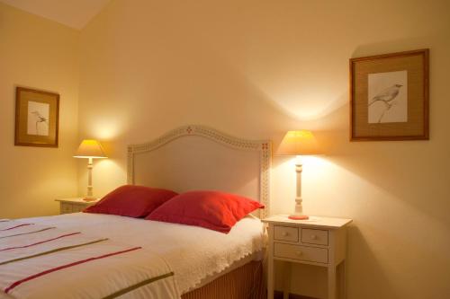 a bedroom with a bed with red pillows and two lamps at Herdades Da Frupor - Casas De Campo in Brejao