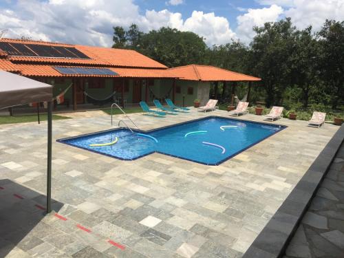 - une piscine avec des chaises et une maison dans l'établissement Estancia Maria, à Pirenópolis