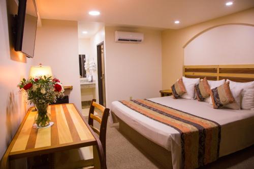 a hotel room with a bed and a table with a vase of flowers at La Villa de Zaragoza in Tijuana