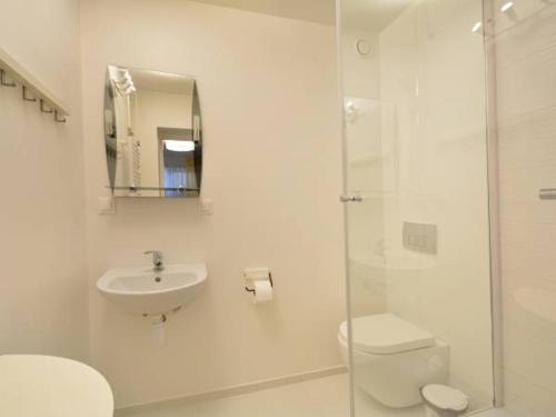 a white bathroom with a toilet and a sink at Akwarium in Międzywodzie