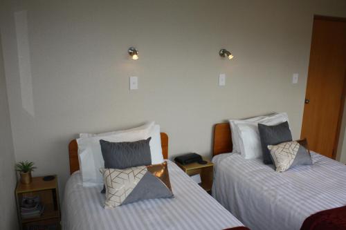 a bedroom with two beds and two lights on the wall at Jenny's Bed & Breakfast in New Plymouth