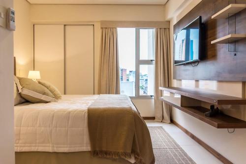 um quarto com uma cama, uma televisão e uma janela em Centro de Asunción Nuevo Apartamento, Cómodo, Seguro, Piscina, Gimnasio y Parking em Assunção
