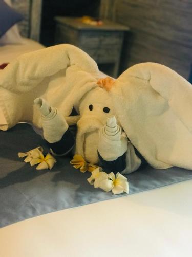 a stuffed elephant laying under a blanket with flowers at D'Yuki Huts Lembongan in Nusa Lembongan