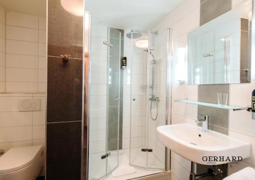 ein Bad mit einer Dusche, einem Waschbecken und einem WC in der Unterkunft Hotel Gerhard in Nürnberg