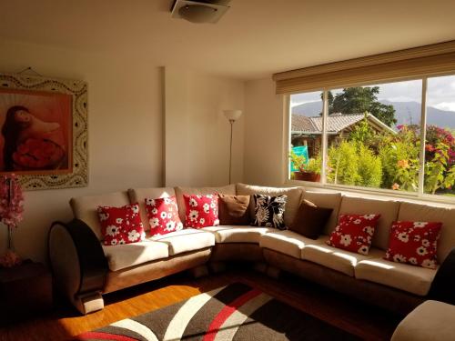 a living room with a couch with red pillows at Hotel Casa Sayu in Tumbaco