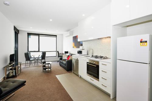 a kitchen with a white refrigerator and a living room at Melbourne Knox Central Apartment Hotel Official in Wantirna