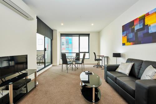 a living room with a couch and a tv at Melbourne Knox Central Apartment Hotel Official in Wantirna