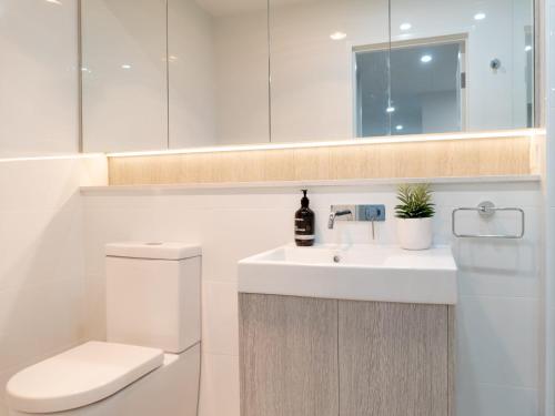 ein Badezimmer mit einem Waschbecken, einem WC und einem Spiegel in der Unterkunft Rockpools 1 in Sawtell