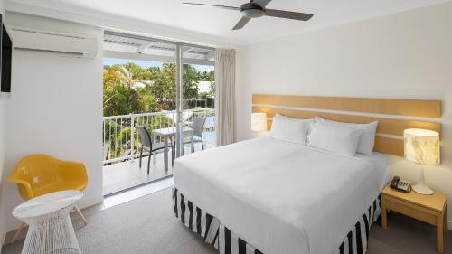 1 dormitorio con 1 cama grande y balcón en Oaks Port Douglas Resort, en Port Douglas