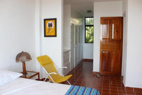 a bedroom with a bed and a yellow chair at Villa La Loma in Ixtapa