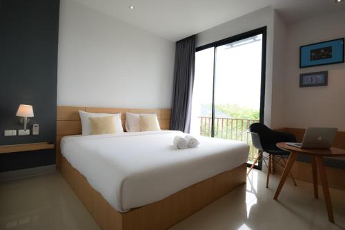 a bedroom with a large bed and a desk with a laptop at B Boutique Residence in Suratthani