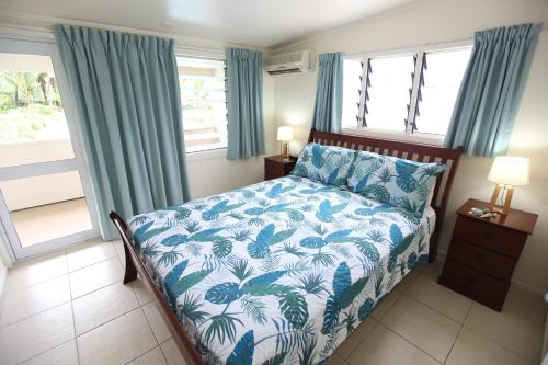 a bedroom with a bed with a blue and white bedspread at Coral Sands Apartments in Rarotonga