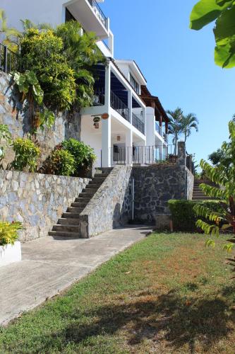 Casa blanca con escaleras y pared de piedra en Villa La Loma, en Ixtapa