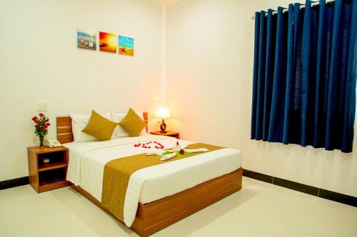 a bedroom with a bed and a blue curtain at PHAM GIA HOTEL Mui Ne in Mui Ne