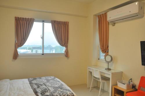 a bedroom with a bed and a desk and a window at CORAL SEA in Taitung City