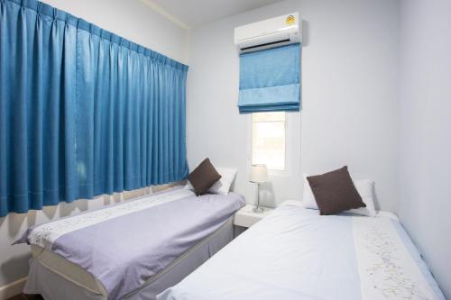 two beds in a room with blue curtains at Arantarakiri Resort Khao Yai in Mu Si