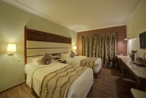 a hotel room with two beds and a sink at Goldfinch Hotel Bangalore in Bengaluru