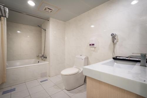a bathroom with a toilet and a sink and a tub at Yoyo Hotel in Chiayi City