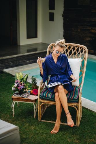 a woman sitting in a chair next to a pool at The Apartments Canggu in Canggu
