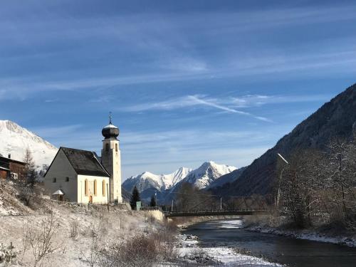 a church next to a river with a bridge and mountains at Alpfee Lechtal in Bach