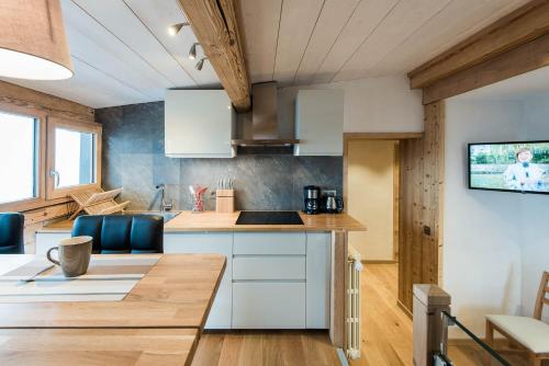 a kitchen with white cabinets and a wooden table at Appartements Caprice des Neiges in Combloux