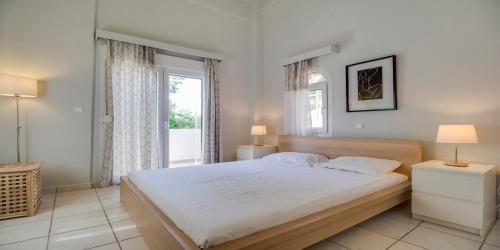 a bedroom with a large bed and a window at Ekatis Houses in Sani in Sani Beach