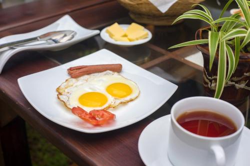 a plate with eggs and bacon and a cup of tea at Green Villa Unawatuna in Unawatuna