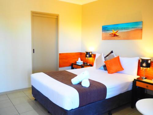 a bedroom with a large white bed with orange pillows at Bella Vista Motel in Gosford