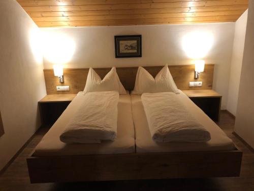a bed with two white pillows and two lights at Riatschhof in Nauders