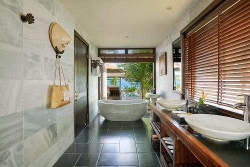 a bathroom with three sinks and a bath tub at Amiana Resort Nha Trang in Nha Trang