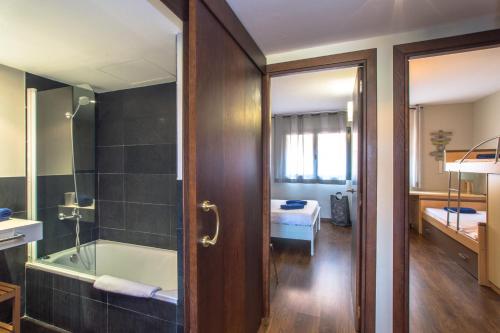 a bathroom with a bath tub and a room with a bed at Costabravaforrent Residencial Albons in Albóns