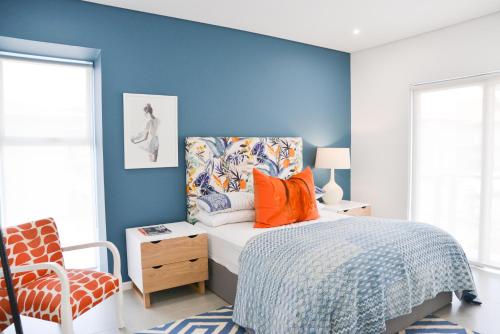 a bedroom with blue walls and a bed with orange pillows at 55 Zimbali wedge Ballito in Ballito